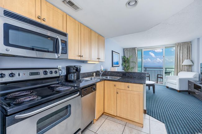 Kitchen with a sink, appliances with stainless steel finishes, visible vents, light brown cabinetry, and a peninsula | Image 8
