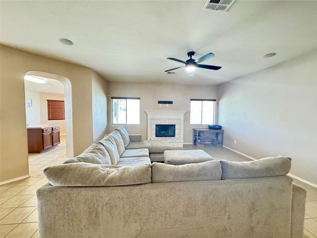 Living area with plenty of natural light, light tile patterned floors, arched walkways, and ceiling fan | Image 7