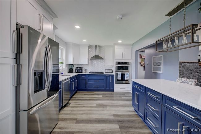 Kitchen with blue cabinetry, wall chimney exhaust hood, stainless steel appliances, light hardwood / wood-style flooring, and white cabinets | Image 33