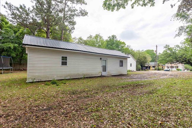 Rear view of house with a trampoline, a yard, and metal roof | Image 24