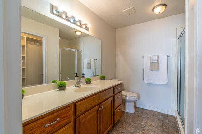 Full bathroom featuring vanity, toilet, baseboards, a shower stall, and visible vents | Image 16