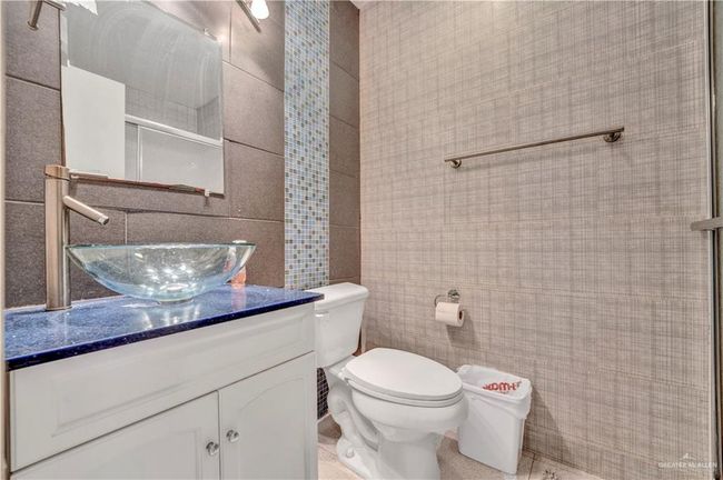 Bathroom featuring tile walls, vanity, toilet, and a shower | Image 11