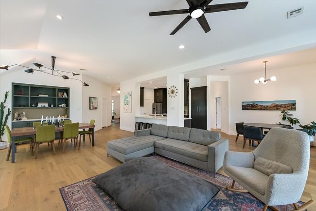 Living room with lofted ceiling, light wood finished floors, a ceiling fan, a chandelier, and recessed lighting | Image 5