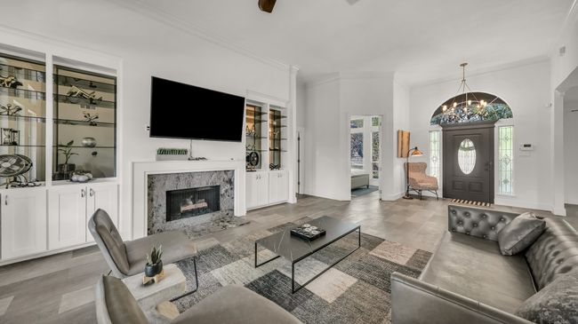 Living room with a chandelier, crown molding, a high end fireplace, and wood finished floors | Image 6