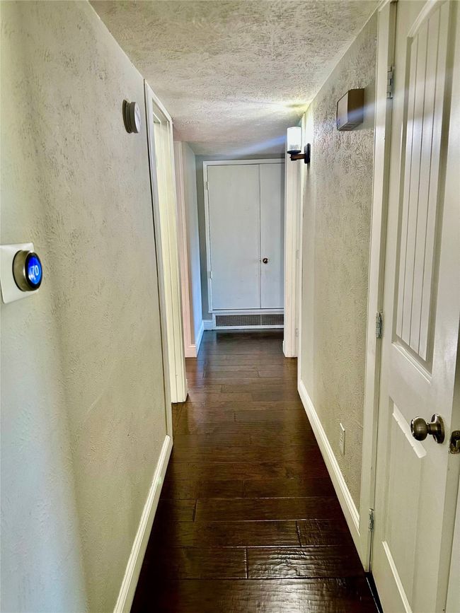 Hall featuring a textured wall, hardwood / wood-style flooring, and a textured ceiling | Image 19