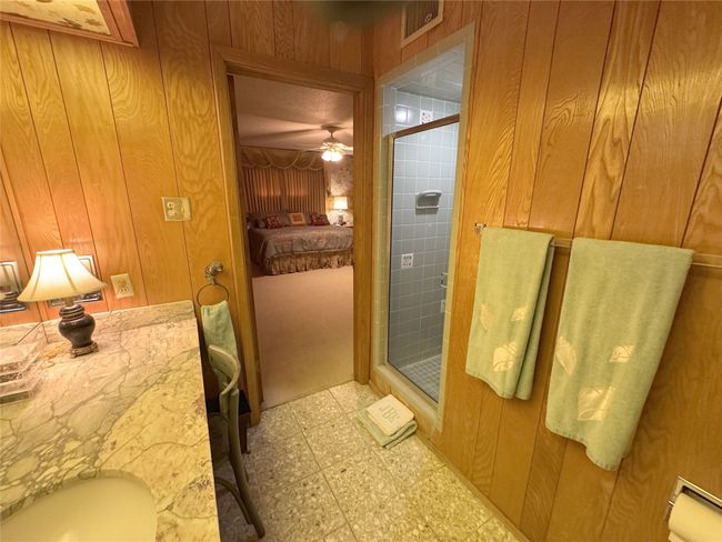 Bathroom featuring tile patterned floors, a stall shower, wood walls, and ceiling fan | Image 33