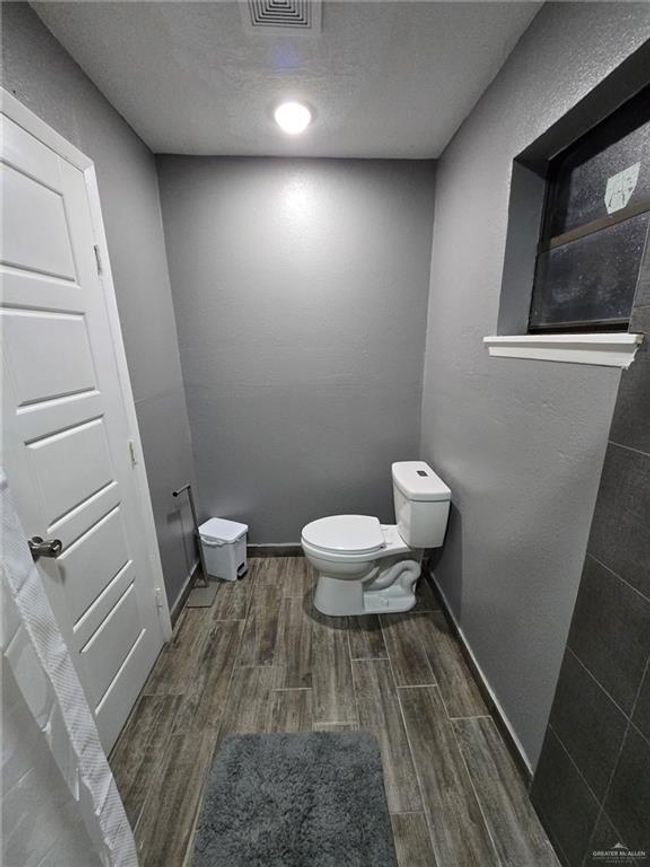 Bathroom featuring wood finished floors, toilet, baseboards, and a textured ceiling | Image 4