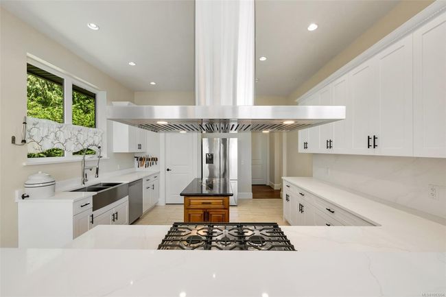 Kitchen with appliances with stainless steel finishes, island exhaust hood, white cabinetry, light stone counters, and recessed lighting | Image 47