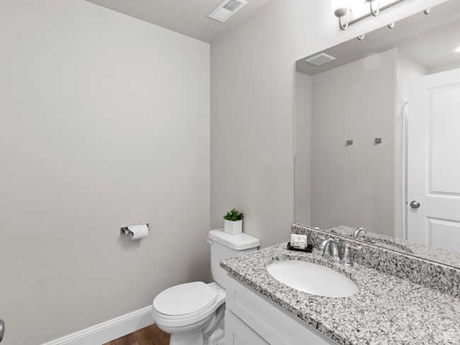 Bathroom featuring vanity, toilet, visible vents, baseboards, and wood finished floors | Image 24