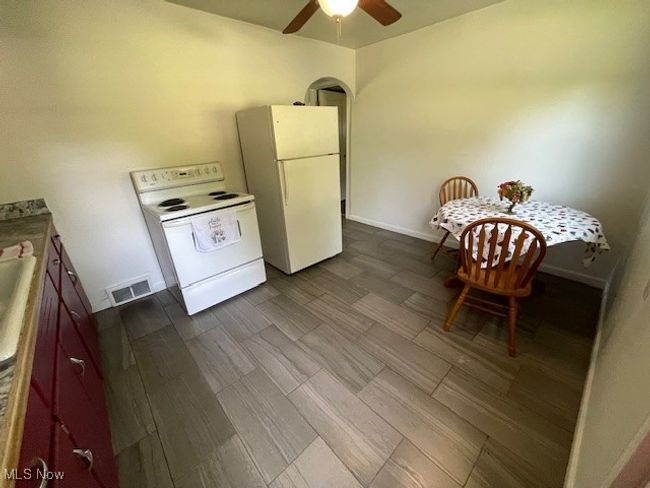 Kitchen featuring white appliances, ceiling fan, dark wood-style flooring, baseboards, and arched walkways | Image 11
