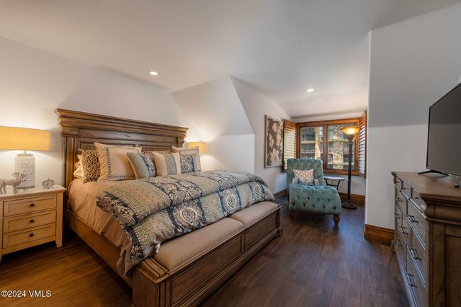 This guest bedroom blends classic mountain style with modern comfort—complete with reading nook, ensuite bath, and natural light spilling through wood-framed windows. | Image 13