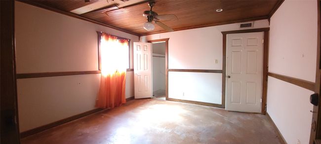 Unfurnished bedroom with concrete floors, wooden ceiling, and a closet | Image 21