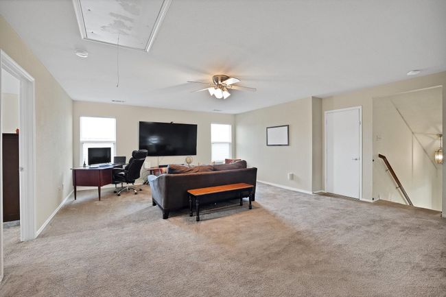 Carpeted living area featuring attic access, an office area, and a ceiling fan | Image 12