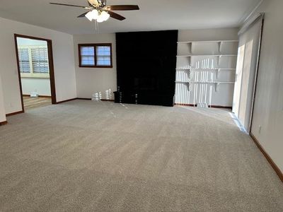 Unfurnished living room featuring carpet flooring, ceiling fan, and a fireplace | Image 3