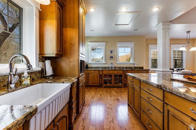 Kitchen with a sink, brown cabinets, light wood finished floors, and ornate columns | Image 6