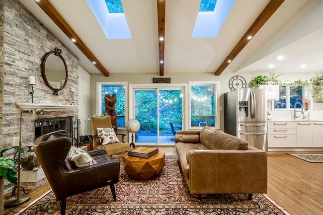 Living area with a skylight, light wood-style flooring, recessed lighting, and a fireplace | Image 4