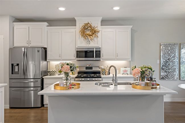 Kitchen featuring sink, dark hardwood / wood-style floors, an island with sink, white cabinets, and appliances with stainless steel finishes | Image 8