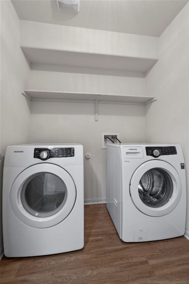 The spacious laundry room allows for a front-loading washer and dryer, overhead shelving, and room for laundry baskets or a rolling cart between the units. | Image 23