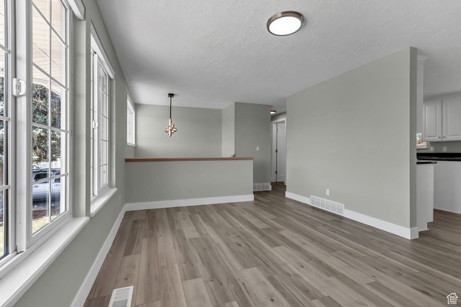 Interior space featuring a textured ceiling, visible vents, baseboards, and light wood-type flooring | Image 9