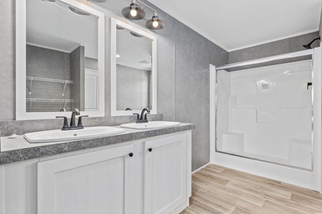 Full bath featuring double vanity, a shower, and wood finished floors | Image 4