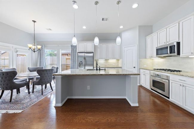 Large island with breakfast bar seating for casual dining and modern pendant lighting above. | Image 9