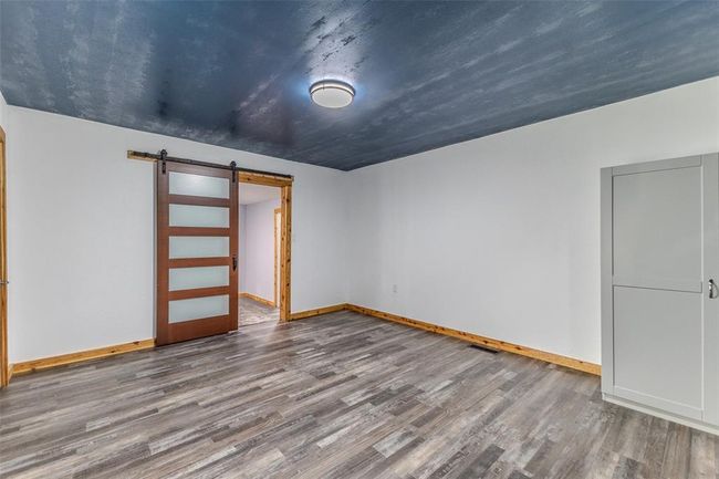 Unfurnished room featuring a barn door, wood finished floors, and baseboards | Image 27