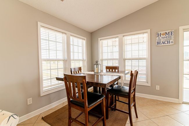Dining area featuring lofted ceiling, light tile patterned floors, baseboards, and healthy amount of natural light | Image 21
