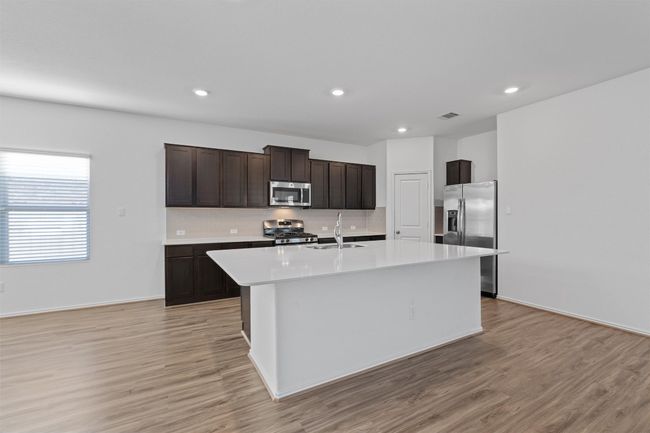 Kitchen with a center island with sink, appliances with stainless steel finishes, light countertops, dark brown cabinets, and a sink | Image 6