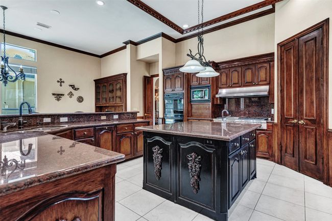 Just past the dining room is the gourmet kitchen of your dreams! Miles of counter space, an abundance of cabinets for storage, a huge center island with carved accents and vegetable sink - Julia Childs may be your new best friend! | Image 11