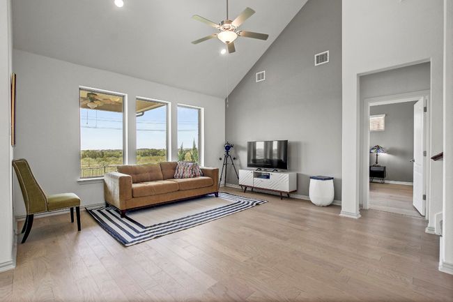 Living area with high vaulted ceiling, a ceiling fan, and wood finished floors | Image 11