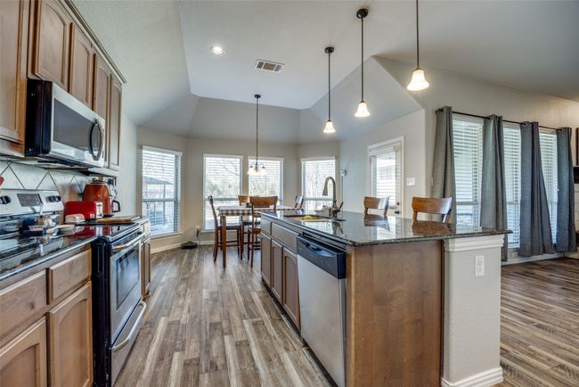 Kitchen with pendant lighting, sink, lofted ceiling, stainless steel appliances, and an island with sink | Image 5