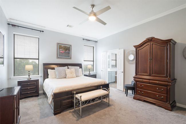 Bedroom with crown molding, light colored carpet, multiple windows, and ensuite bathroom | Image 22