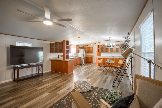 Living area featuring a chandelier, wood finished floors, ceiling fan, and lofted ceiling | Image 10