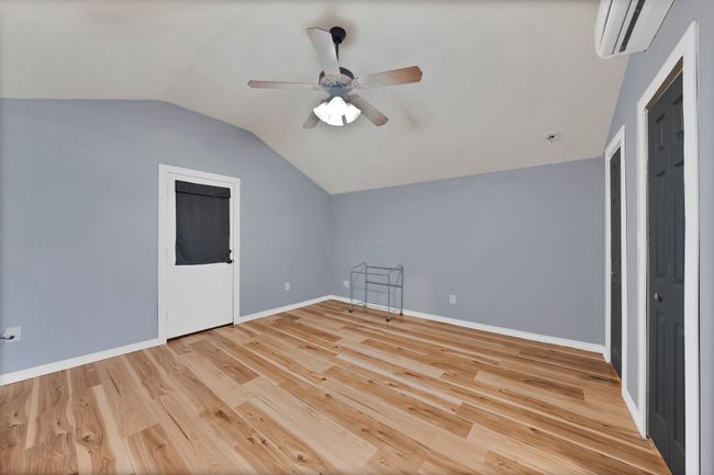 Additional living space with vaulted ceiling, a wall mounted AC, wood finished floors, and a ceiling fan | Image 12