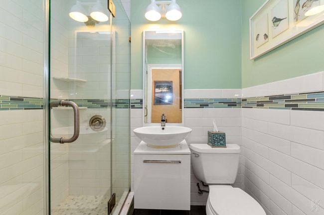 Full bath featuring toilet, a shower stall, vanity, wainscoting, and tile walls | Image 11