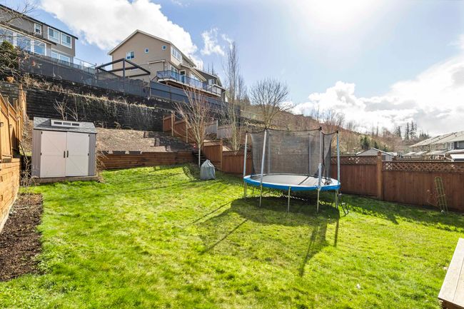 View of yard featuring an outdoor structure, a storage unit, a fenced backyard, and a trampoline | Image 37