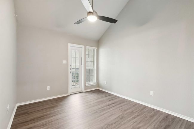 Unfurnished room with ceiling fan, wood finished floors, and high vaulted ceiling | Image 9