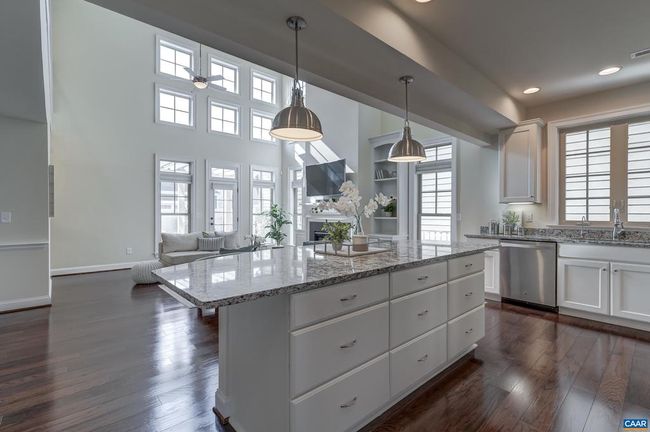 Gourmet kitchen with white cabinets and granite counterops opens to the soaring great room. | Image 6
