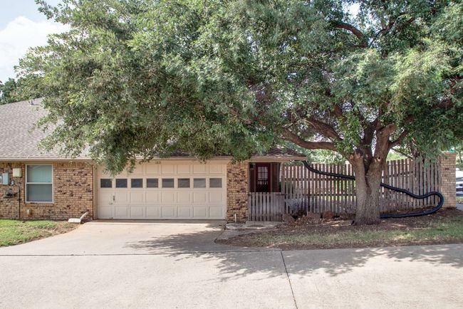 Obstructed view of property featuring an attached garage, brick siding, driveway, and roof with shingles | Image 24