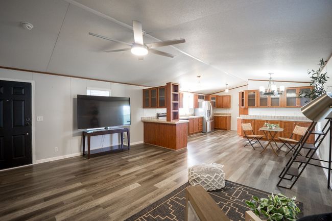 Living room featuring vaulted ceiling, wood finished floors, a chandelier, ceiling fan, and crown molding | Image 14