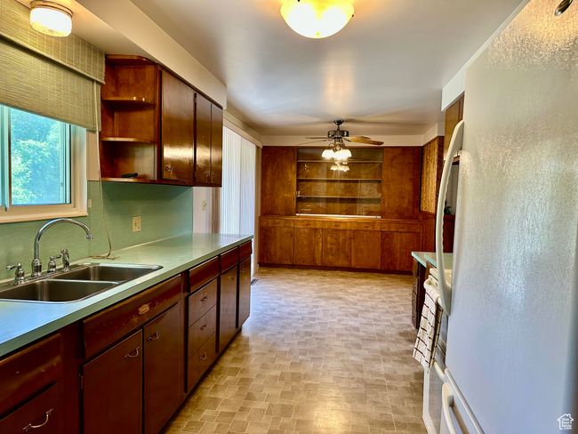 Kitchen featuring window for backyard views, freestanding refrigerator, ceiling fan, and open shelves | Image 6