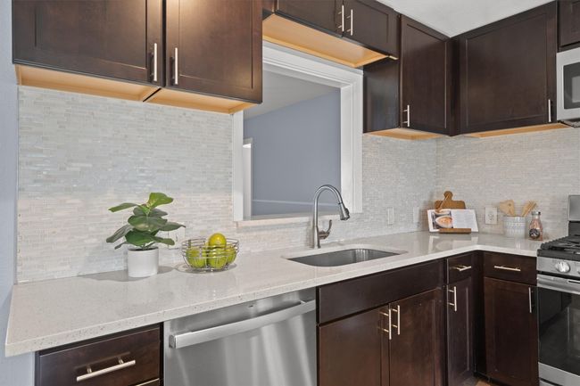 Kitchen featuring decorative backsplash, dark brown cabinets, appliances with stainless steel finishes, and a sink | Image 14