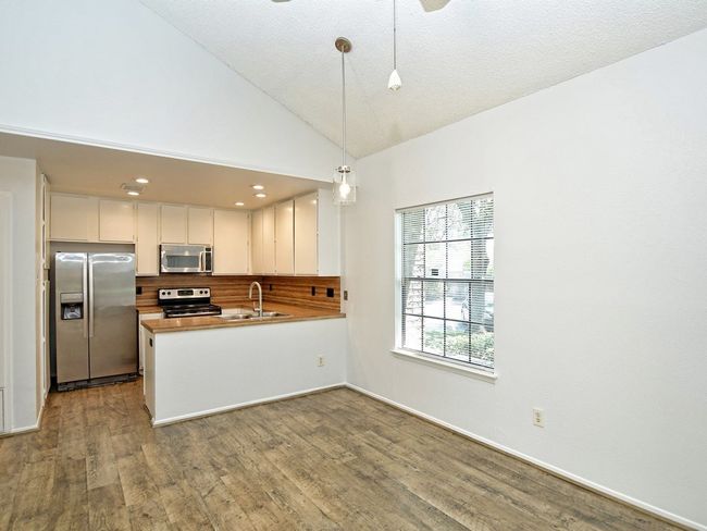 Kitchen with a sink, dark wood-style flooring, stainless steel appliances, backsplash, and hanging light fixtures | Image 5