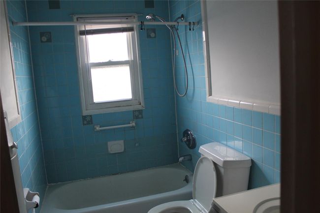 Full bathroom featuring tiled shower / bath, vanity, toilet, and tile walls | Image 6