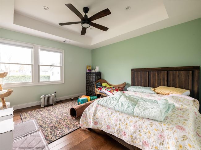 Bedroom featuring a tray ceiling, radiator, baseboards, visible vents, and hardwood / wood-style floors | Image 20