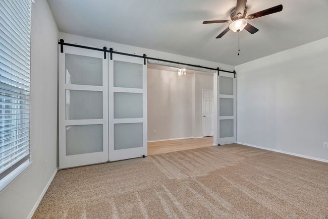 Game room or office featuring a barn door, carpet floors, and a ceiling fan | Image 6