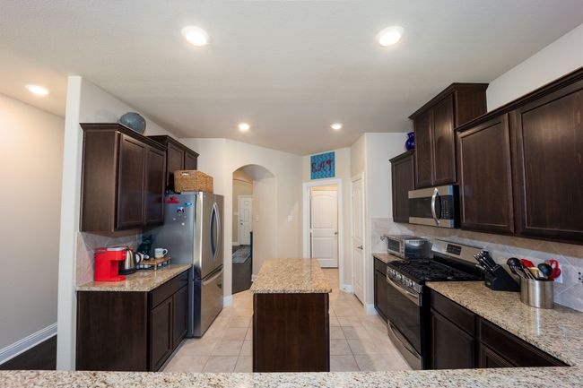 Kitchen featuring appliances with stainless steel finishes, arched walkways, tasteful backsplash, dark brown cabinetry, and recessed lighting | Image 5