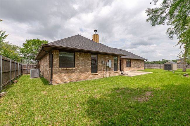 Back of house featuring a storage shed, a chimney, a patio, and a fenced backyard | Image 30