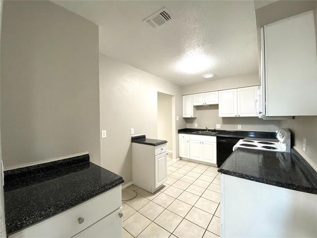 8836 Kitchen with white cabinets, light tile flooring, white stove, and sink | Image 18