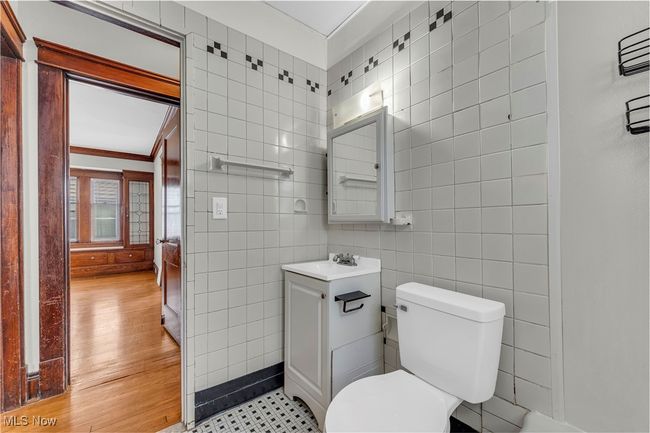Bathroom featuring tile walls, vanity, toilet, ornamental molding, and wood finished floors | Image 20